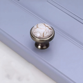Antique ceramic and zinc cabinet handle from Brass Essence, showcasing a vintage design with decorative ceramic top and metal base.