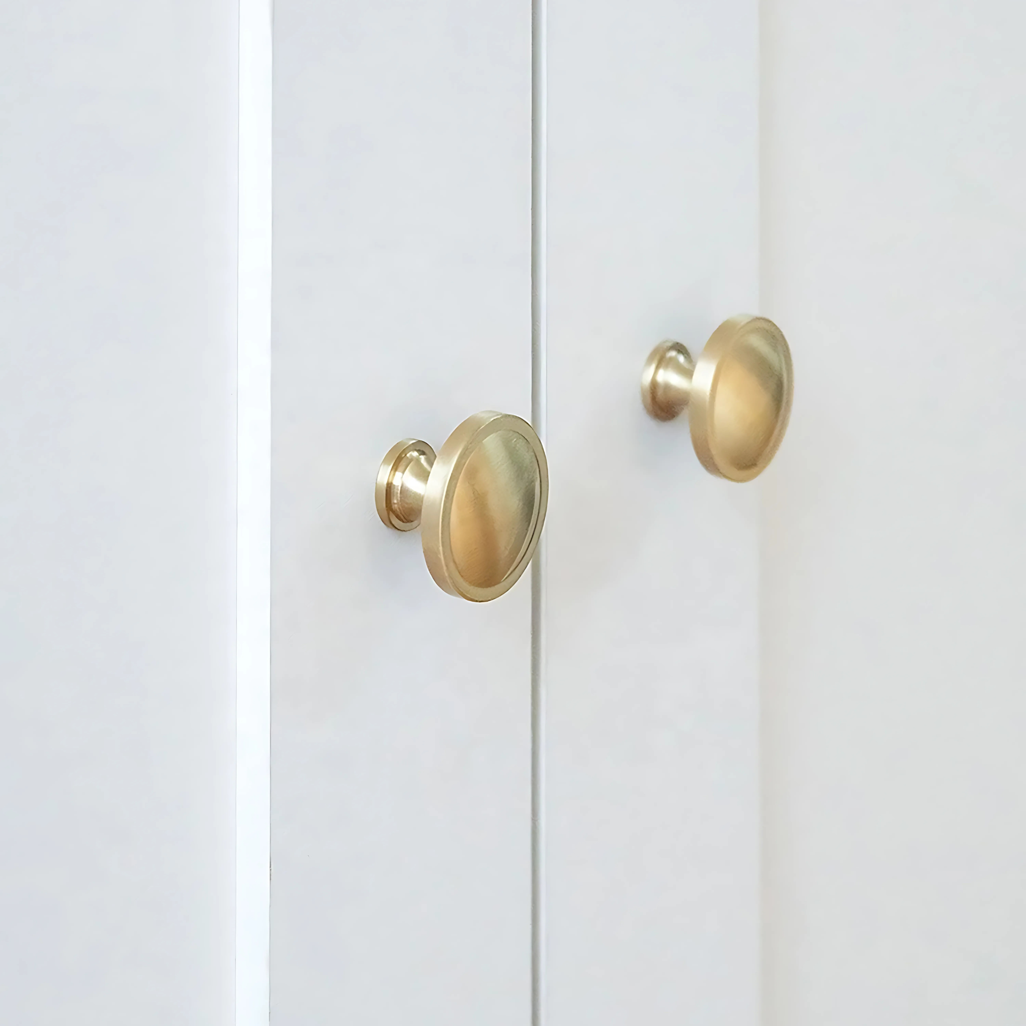 Brass Essence Krisha brushed brass round cabinet knob on a white background, showcasing smooth, circular design and polished finish.