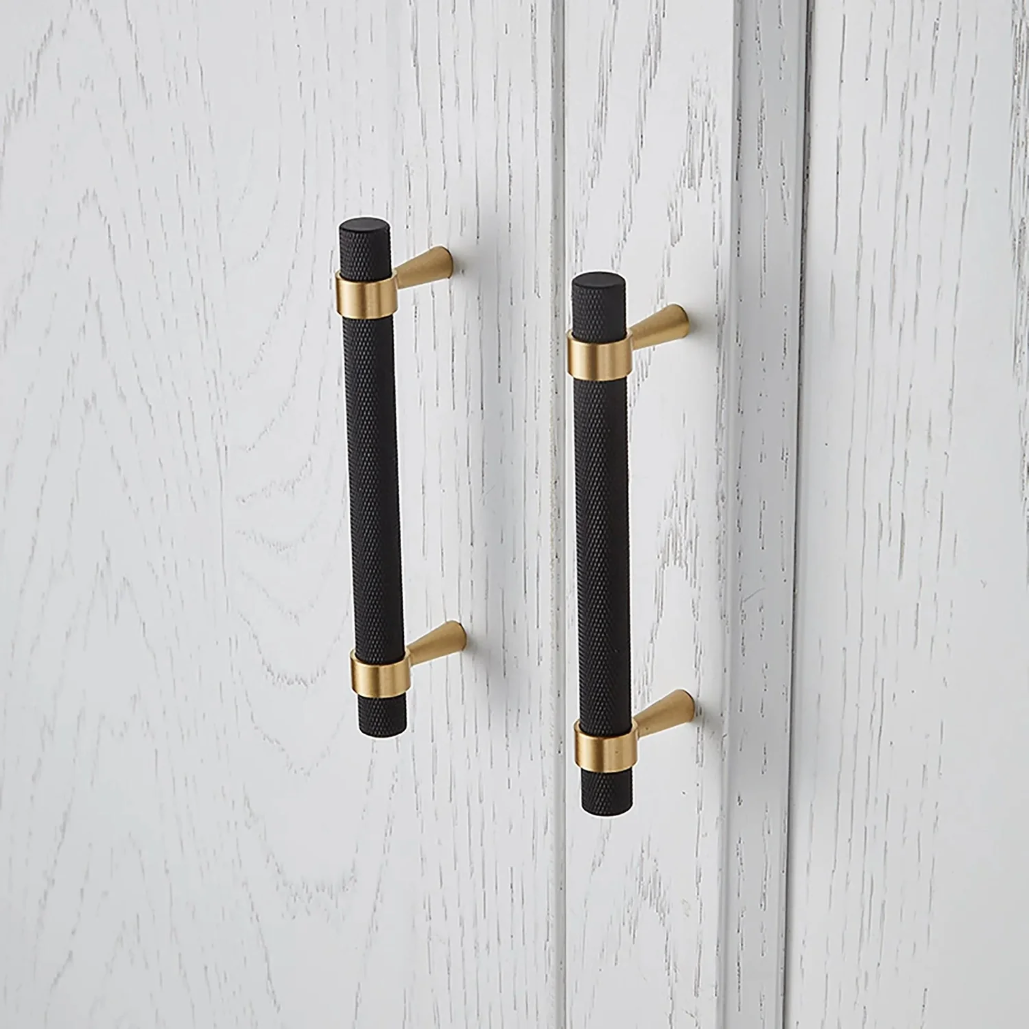Brass Essence knurled black and gold T-bar handle collection, close-up of two T-bar handles with textured grip and polished finish.
