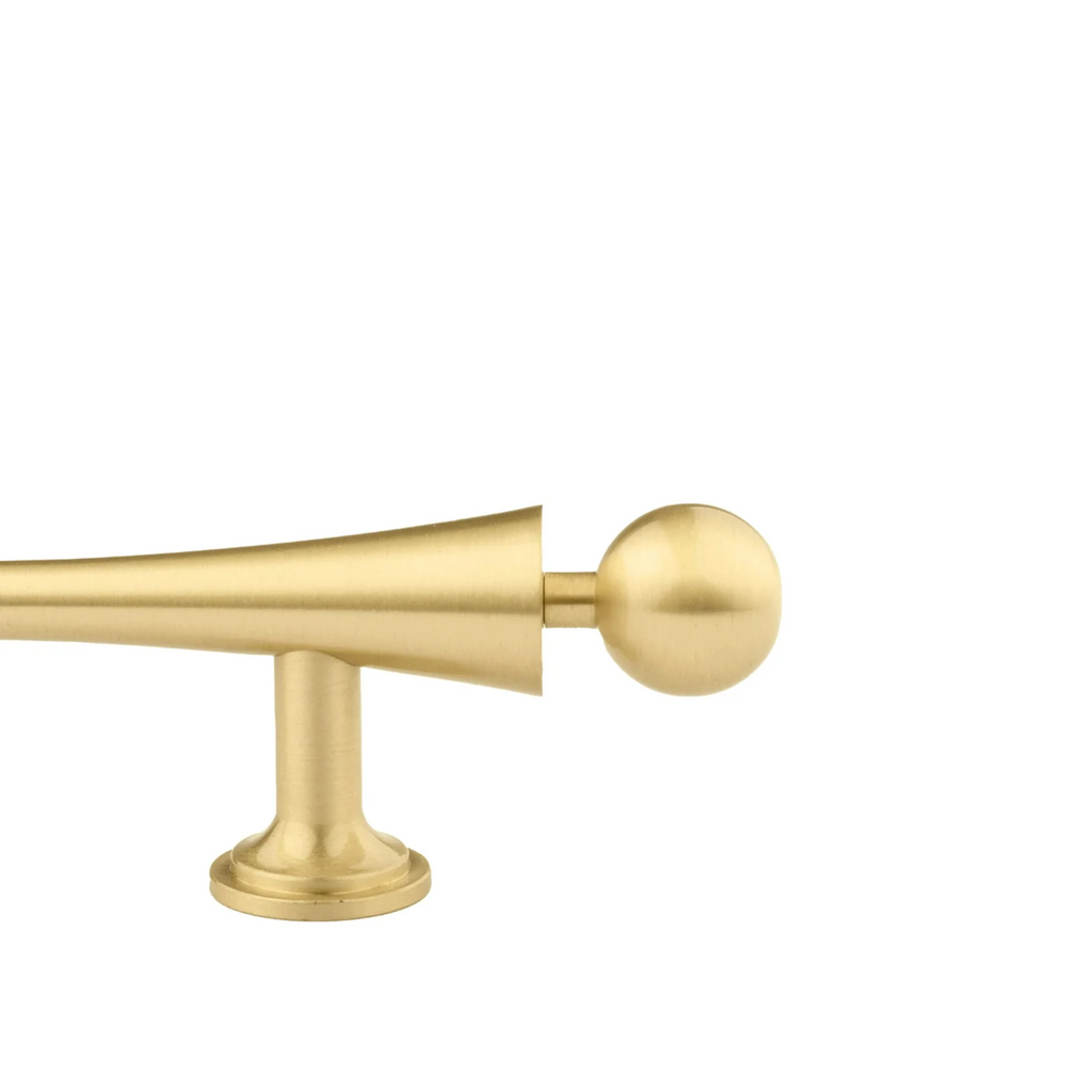 Brass Essence Seasaw Hourglass brushed brass cabinet handle with sleek hourglass shape on a wooden cabinet surface.