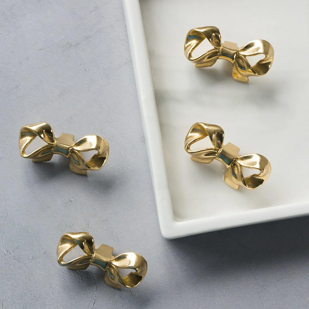 Polished brass bow cabinet knob by Brass Essence, featuring a smooth, shiny finish and elegant bow shape for furniture decor.