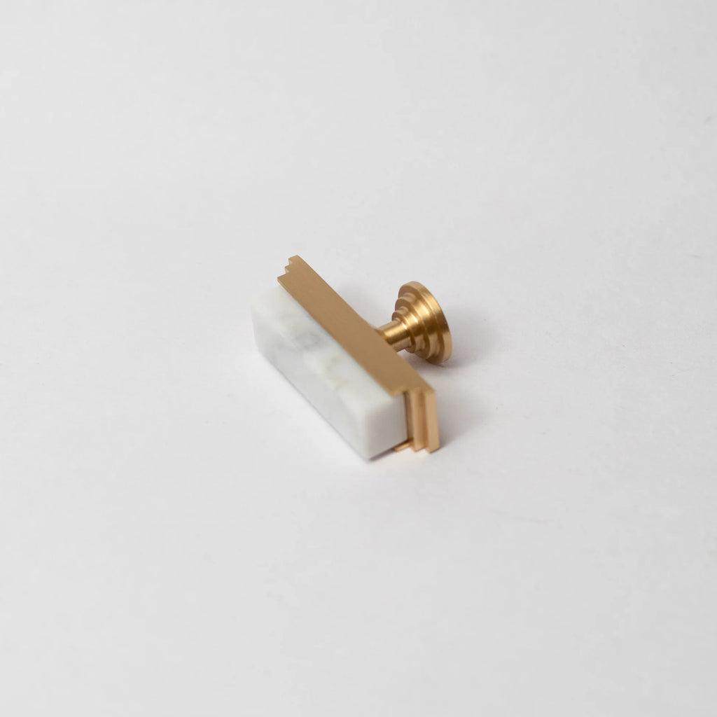 White marble and brass T-bar handle by Brass Essence with modern design on a side view of the Arjun marble knob.