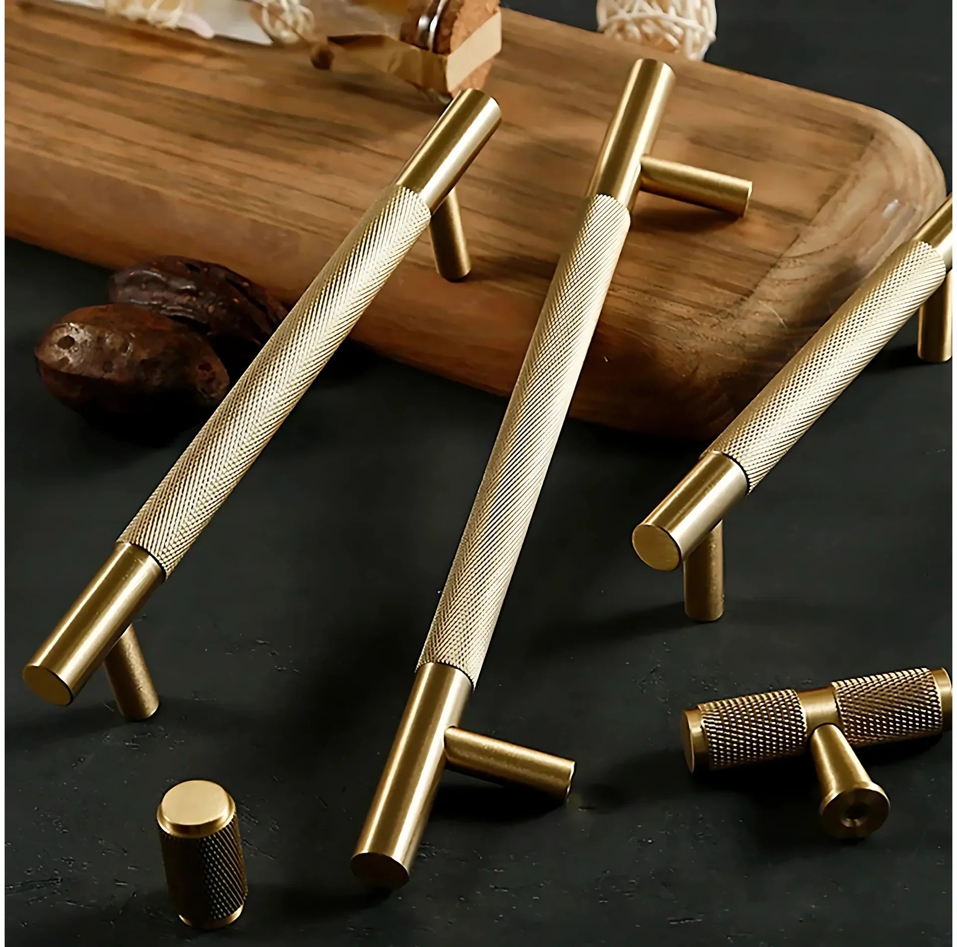 Gold door handles on a dark surface with a wooden board in the background