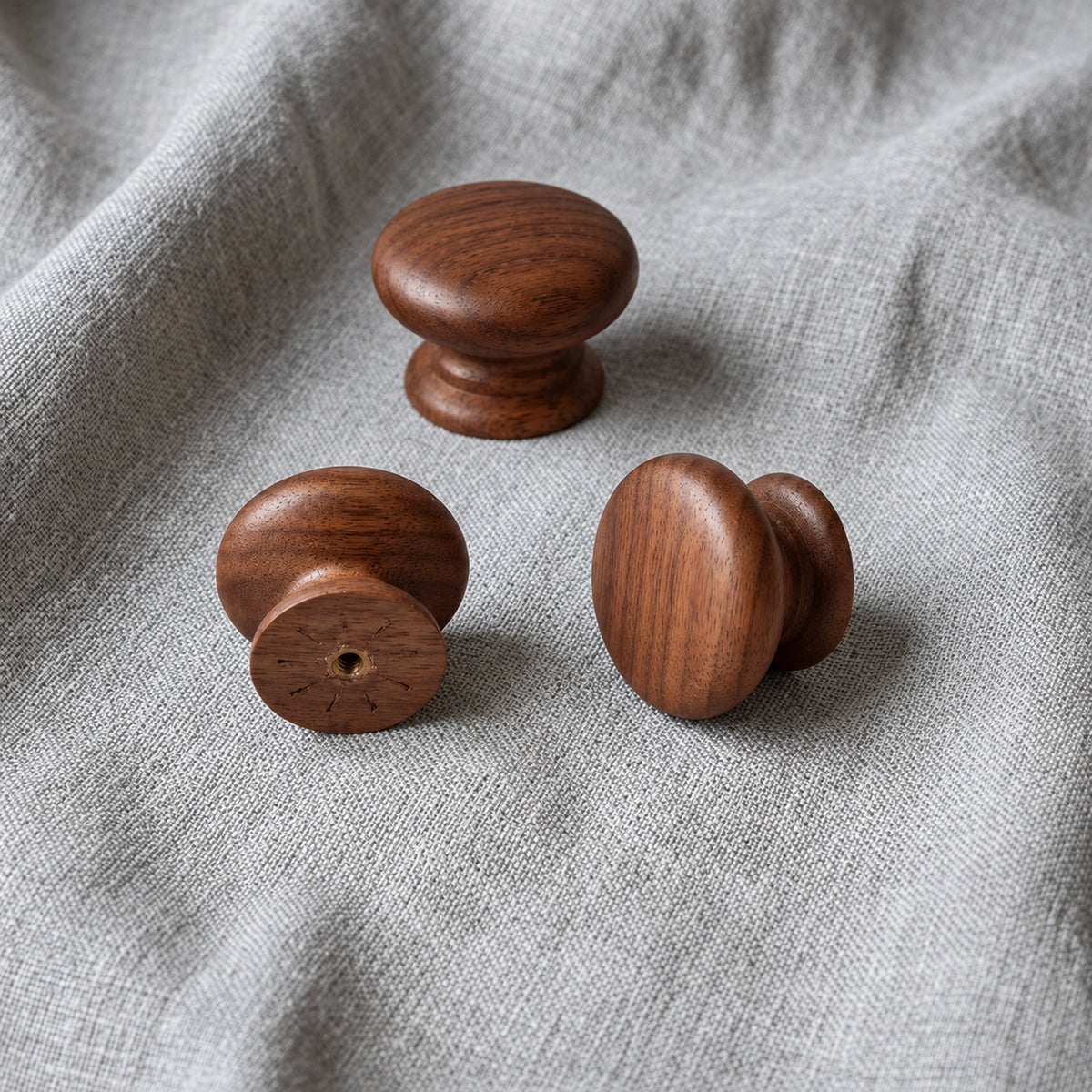 Tectona walnut wooden cabinet knobs on grey fabric showing front, side and rear views – Brass Essence